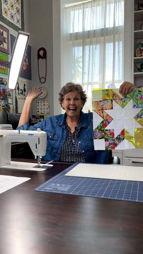 a woman sitting at a sewing machine with her hands up in the air and smiling