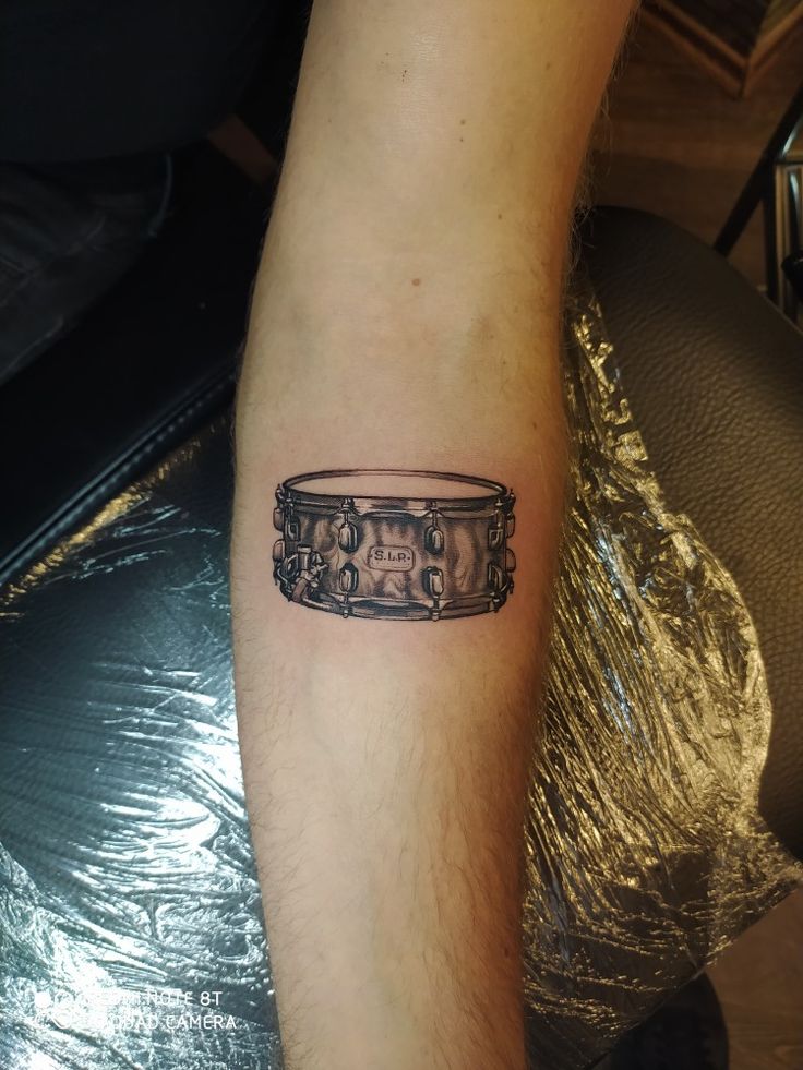 a man's arm with a tattoo on it that has an image of a drum