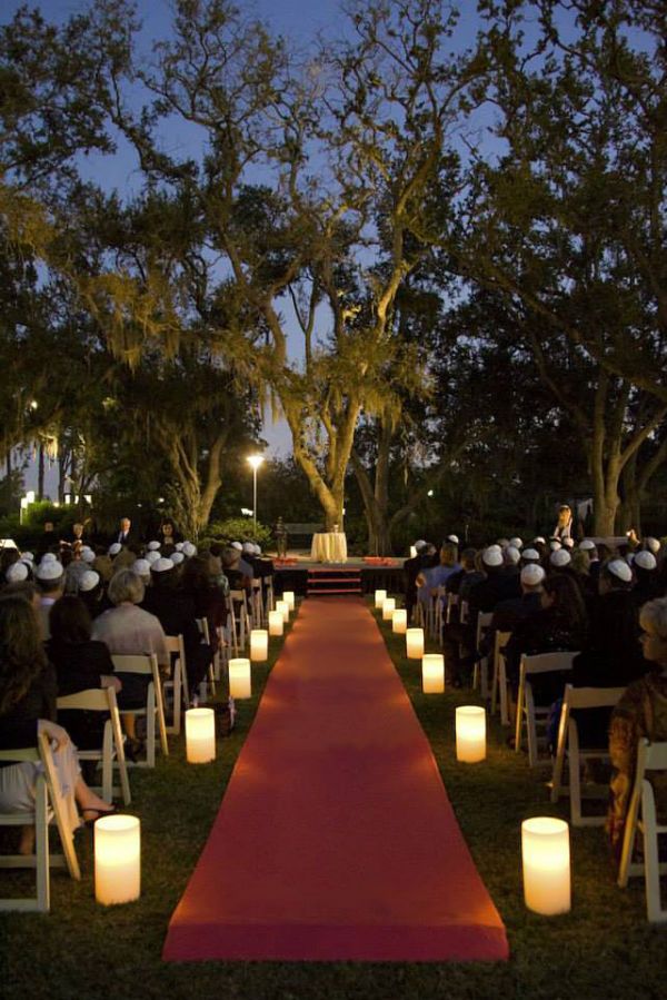 an outdoor ceremony with rows of chairs and lit candles