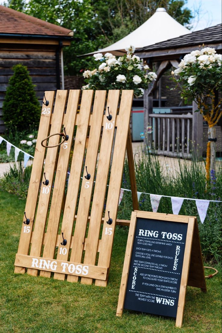 two wooden boards sitting in the grass next to a sign that says ring tosses