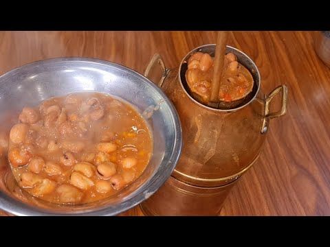 a metal bowl filled with beans next to a copper cup