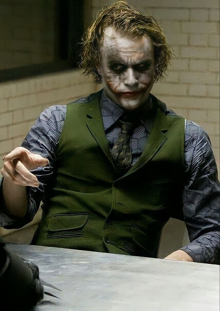 a man dressed as the joker sitting at a table