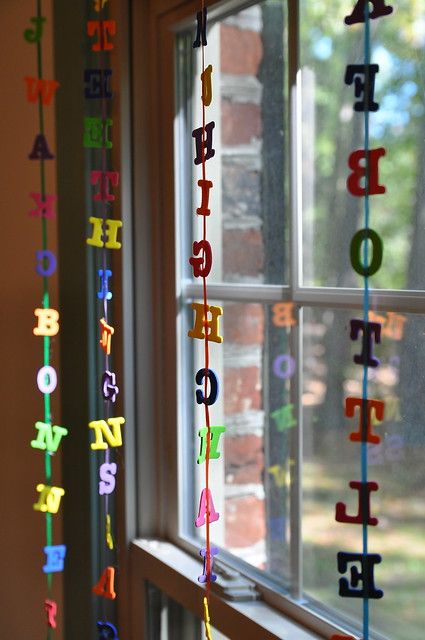 colorful streamers hanging from a window in front of a brick building with trees outside