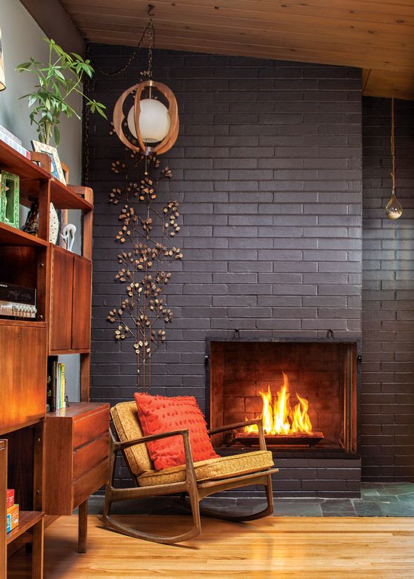 a living room filled with furniture and a fire place in front of a brick wall