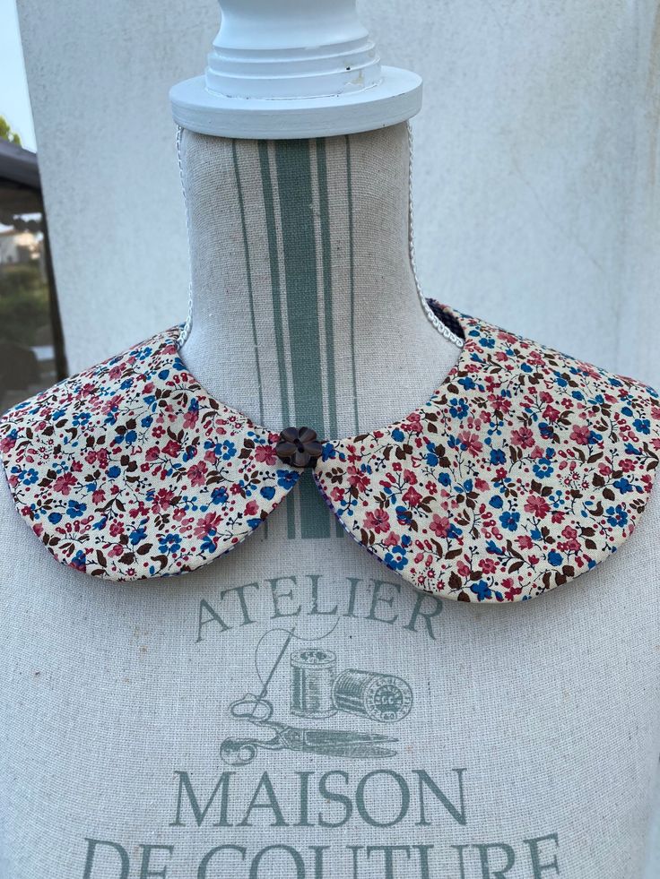 a white mannequin with red, blue and green flowers on it's neck