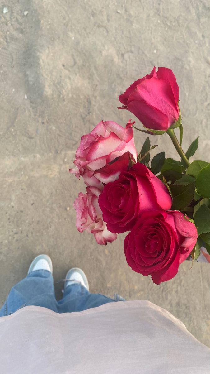 a person's feet are shown next to a bouquet of roses on the ground