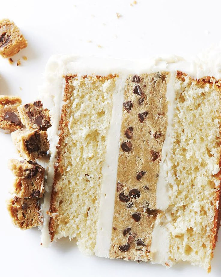 a slice of cake with white frosting and chocolate chips