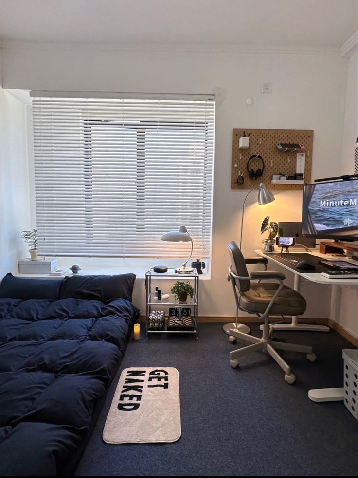 a room with a bed, desk and computer