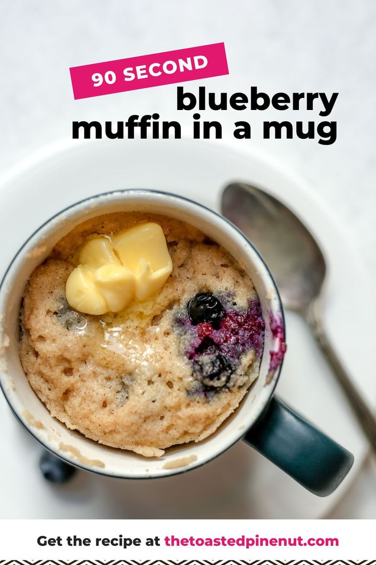 blueberry muffin in a mug with butter on top and spoon next to it