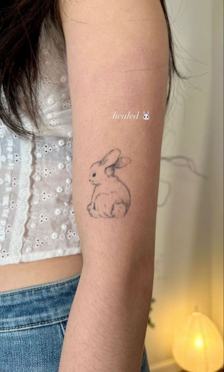 a woman's arm with a small rabbit tattoo on the left side of her arm