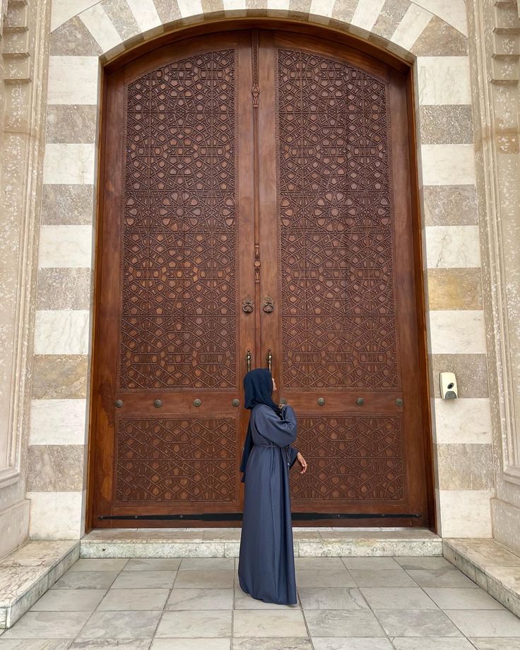 a woman standing in front of a wooden door with a burka veil on her head