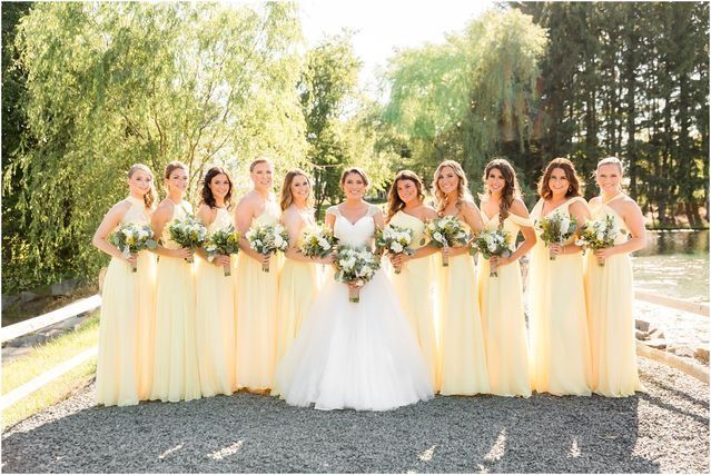 a group of women standing next to each other in front of trees and water wearing yellow dresses