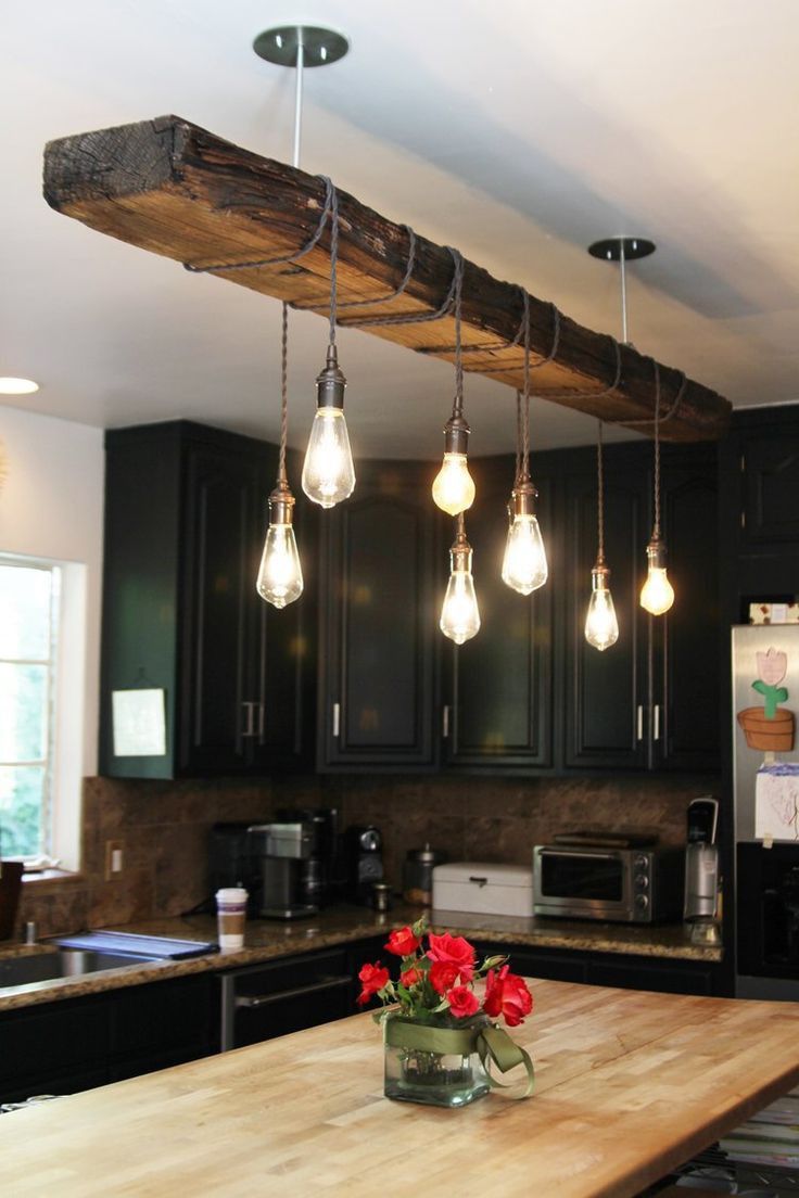 a kitchen with lights hanging from the ceiling and flowers in a vase on the counter