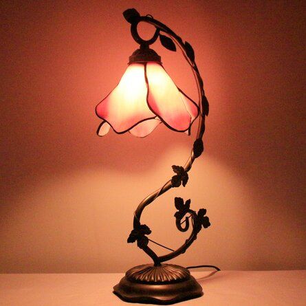 a lamp that is sitting on top of a table next to a light fixture with a flower design