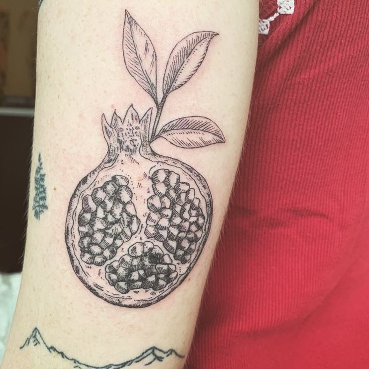 a pomegranate tattoo on the left arm