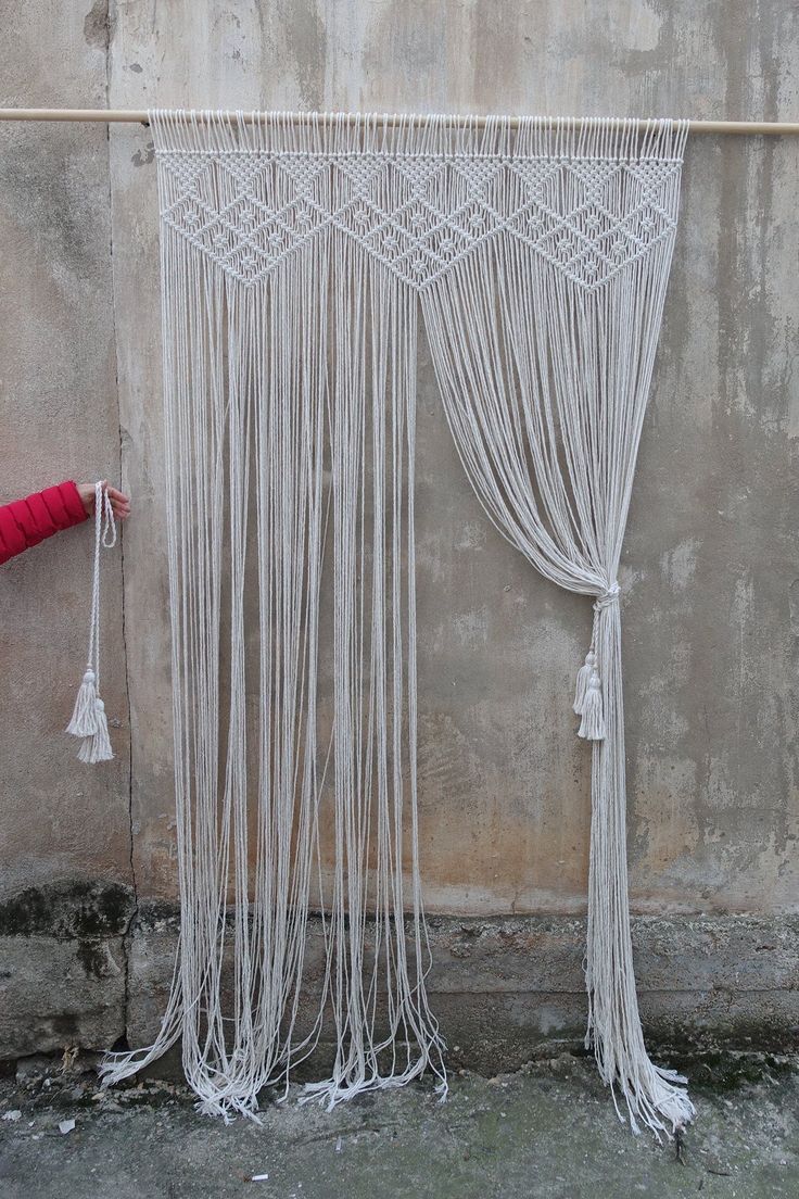 a red umbrella sitting next to a white curtain on the side of a building with tassels hanging from it's sides