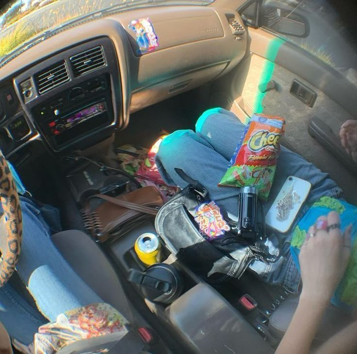 a person sitting in the back seat of a car with food and drinks on it