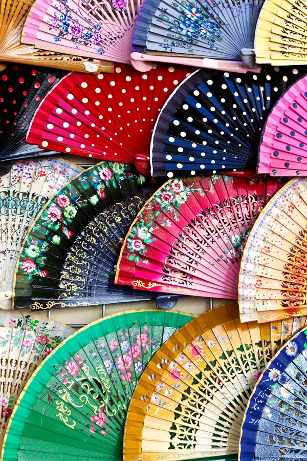 many colorful hand fans are lined up on the wall with polka dots and flowers in them