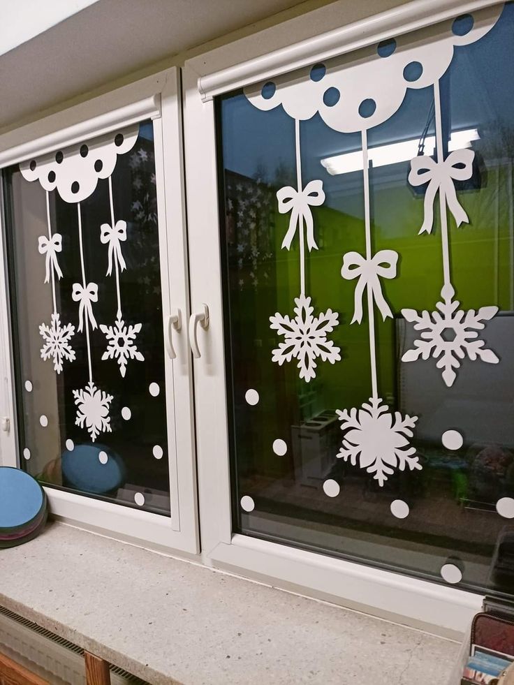 two windows decorated with white snowflakes and bows