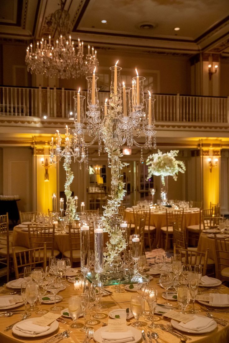 an elegant centerpiece with candles and flowers is displayed on a round table in the ballroom