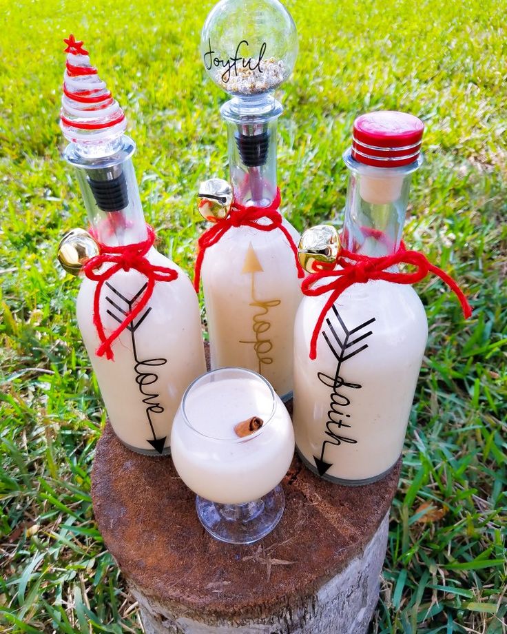 three bottles with candles are sitting on a tree stump