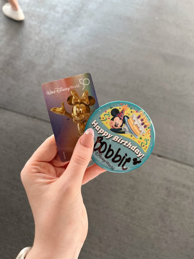 a person holding up a mickey mouse birthday card