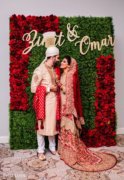 a bride and groom standing in front of a flower wall with the word'bright & romantic'on it