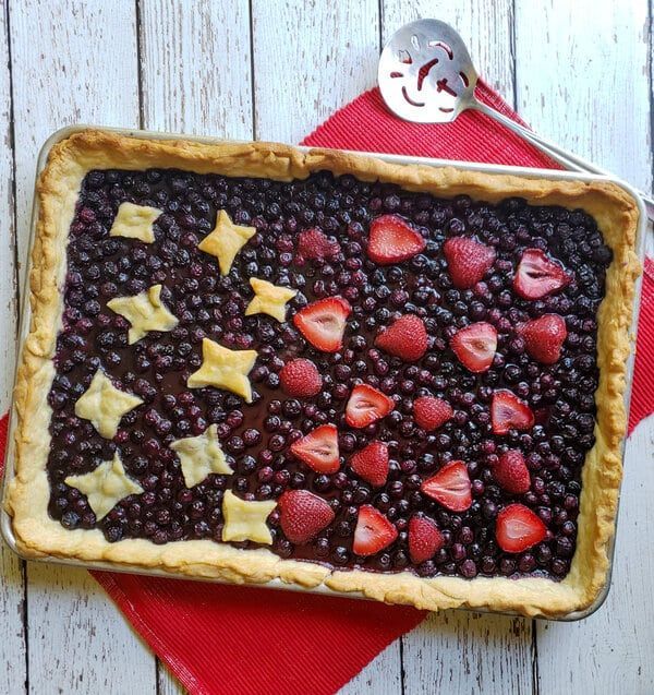 a pie with berries and stars on it sitting on top of a red place mat