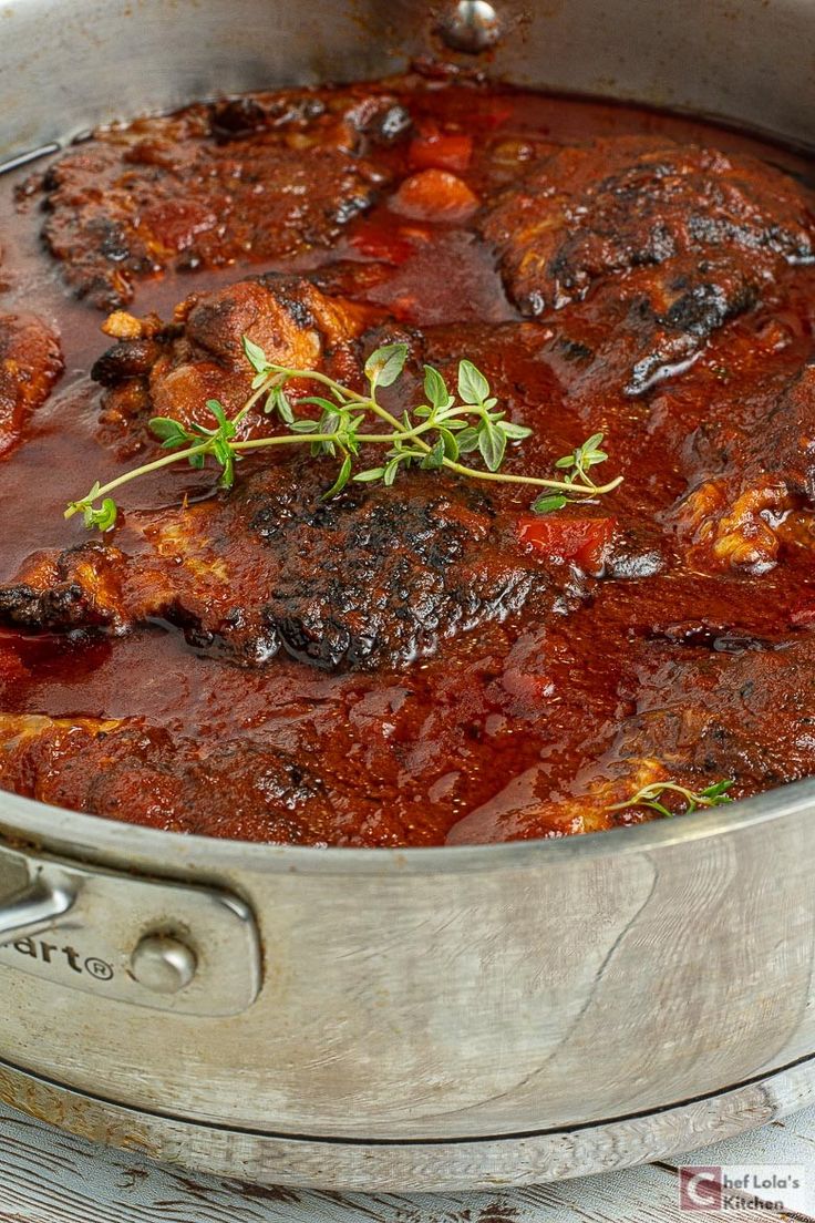 a pot filled with meat and sauce on top of a wooden table