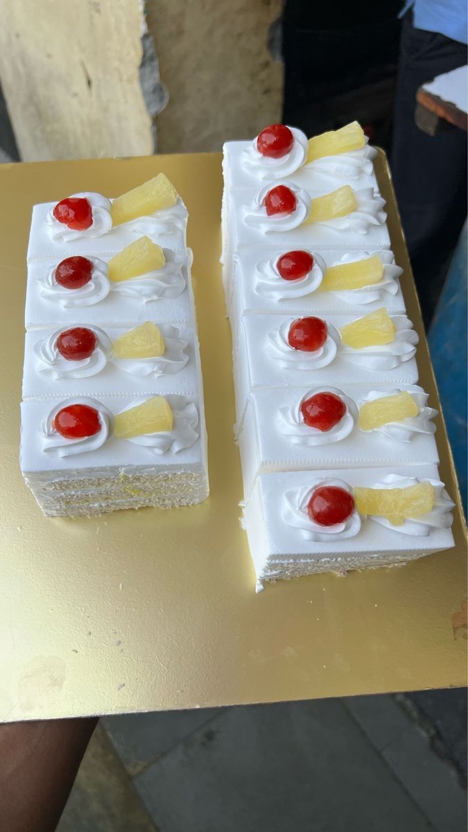 two slices of pineapple cake with cherries on them sitting on a yellow table