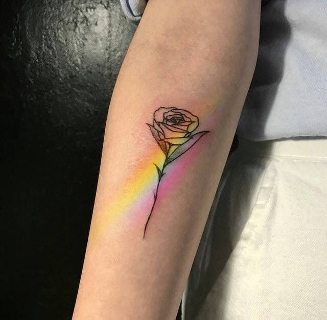 a single rose tattoo on the left inner arm with a rainbow in the middle and a black outline