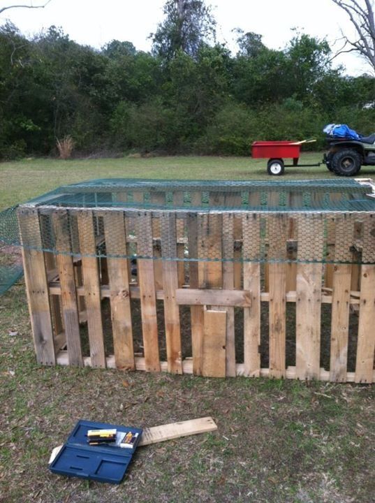 a fence made out of wooden pallets with a tractor in the background