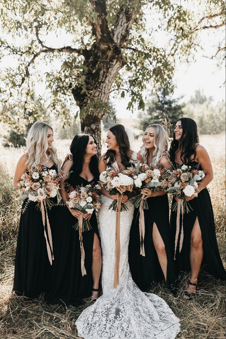 a group of women standing next to each other in front of a tree with flowers