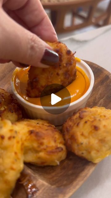 a person dipping sauce into some food on a wooden plate