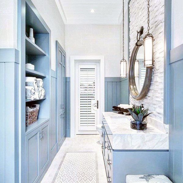 a blue and white bathroom with built - in shelving, sink, and mirror