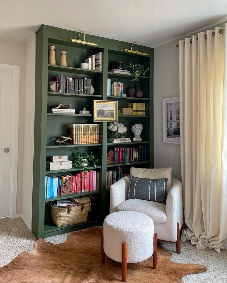 a living room filled with lots of green bookshelves next to a white chair