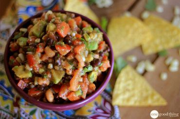 a purple bowl filled with beans and veggies next to tortilla chips