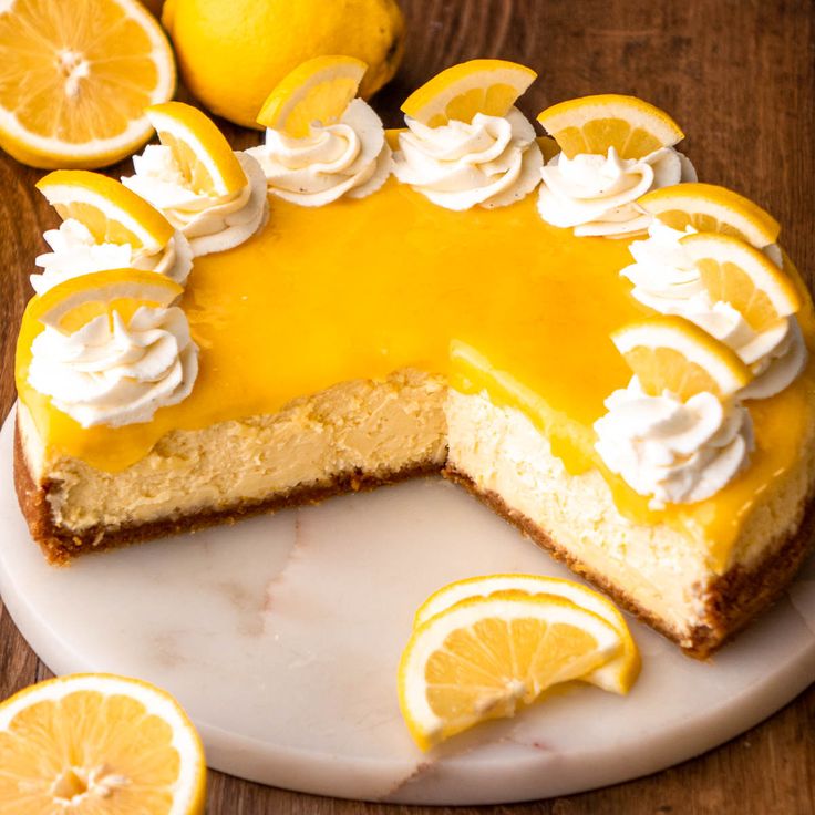 a cheesecake with lemons and meringue on a white plate next to sliced lemons