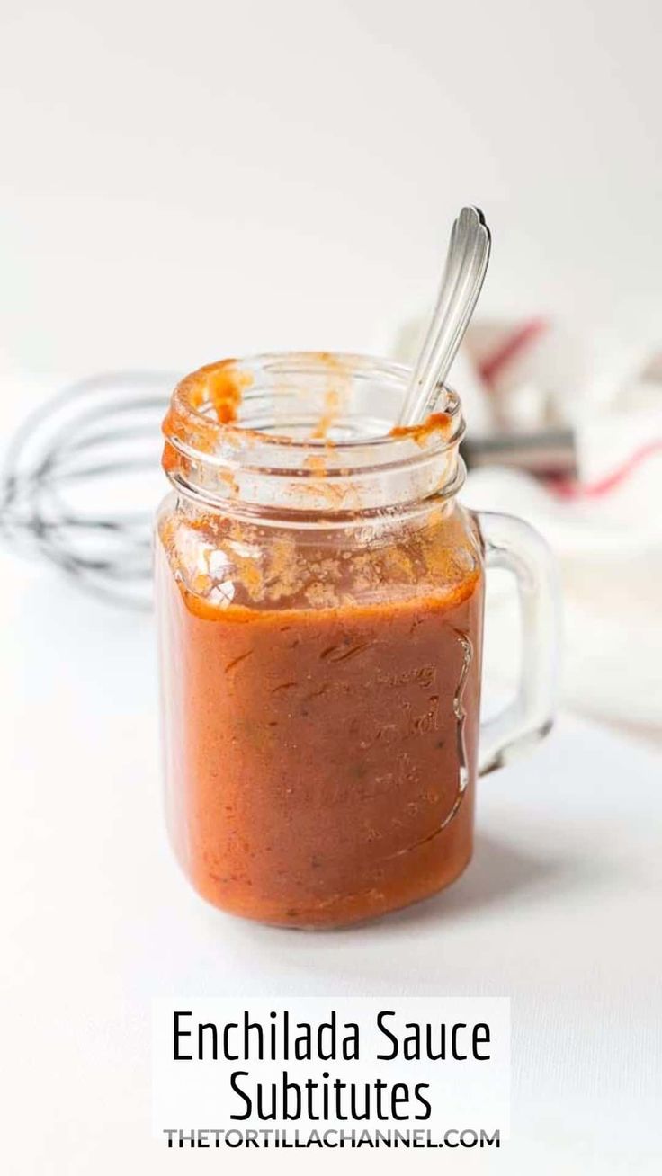 a glass jar filled with sauce sitting on top of a white table next to a sign that says enchilada sauce subtitues