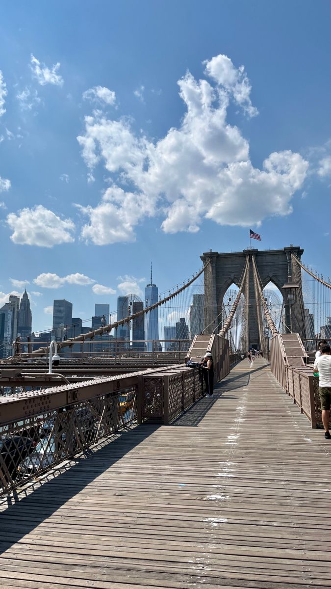 people walking across the brooklyn bridge on a sunny day