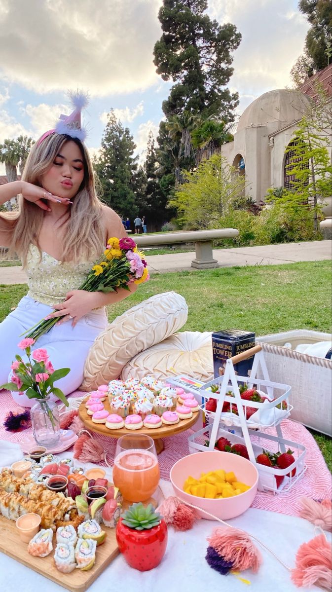 a woman in a white dress sitting at a table with food and drinks on it