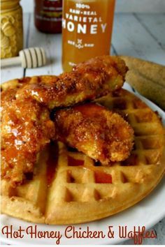 fried chicken and waffles on a white plate with honey in the back ground