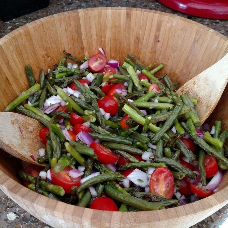 a wooden bowl filled with green beans and tomatoes