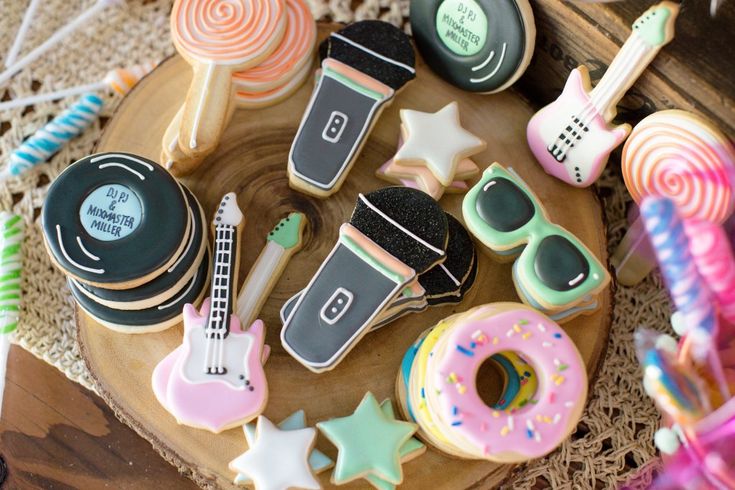 some decorated cookies are sitting on a wooden platter next to other treats and decorations