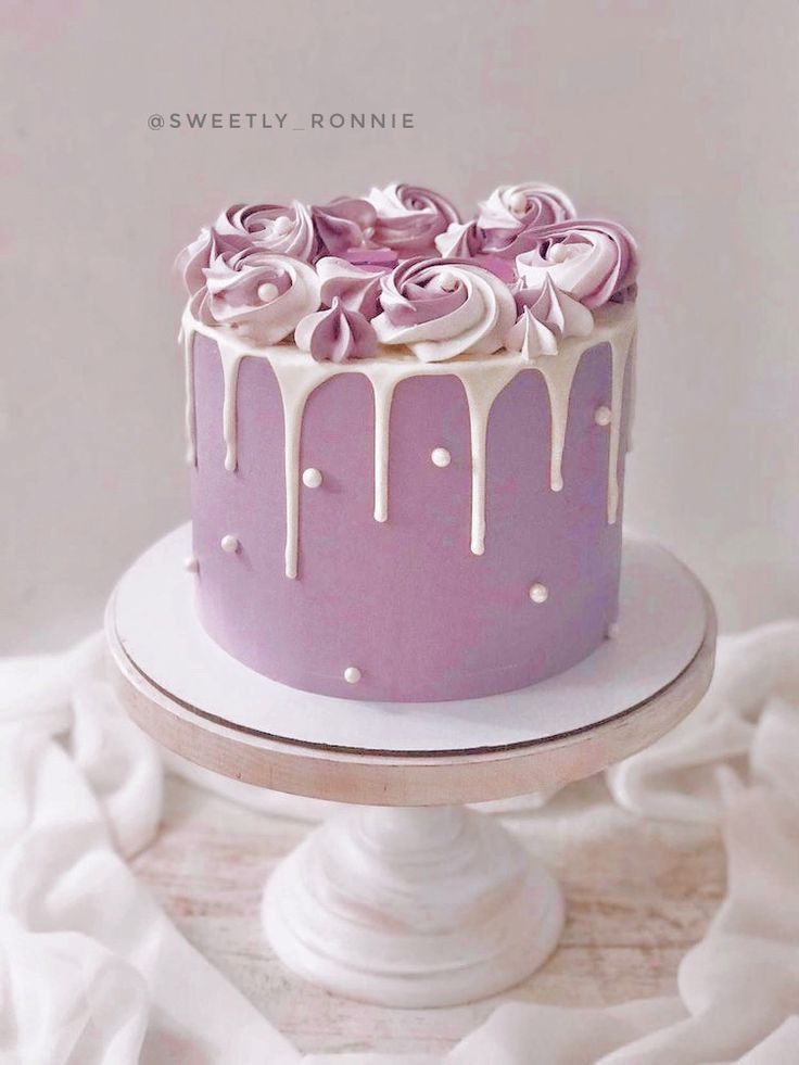 a purple cake with white icing and roses on top