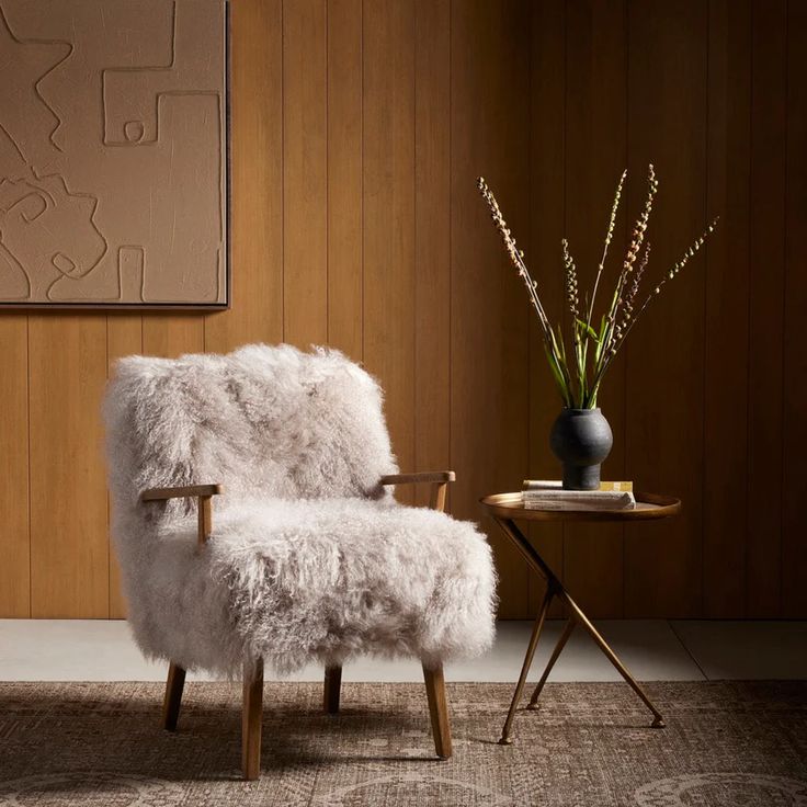 a white chair sitting on top of a rug next to a table with a vase