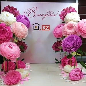 pink and white flowers on display in front of a sign that says supama