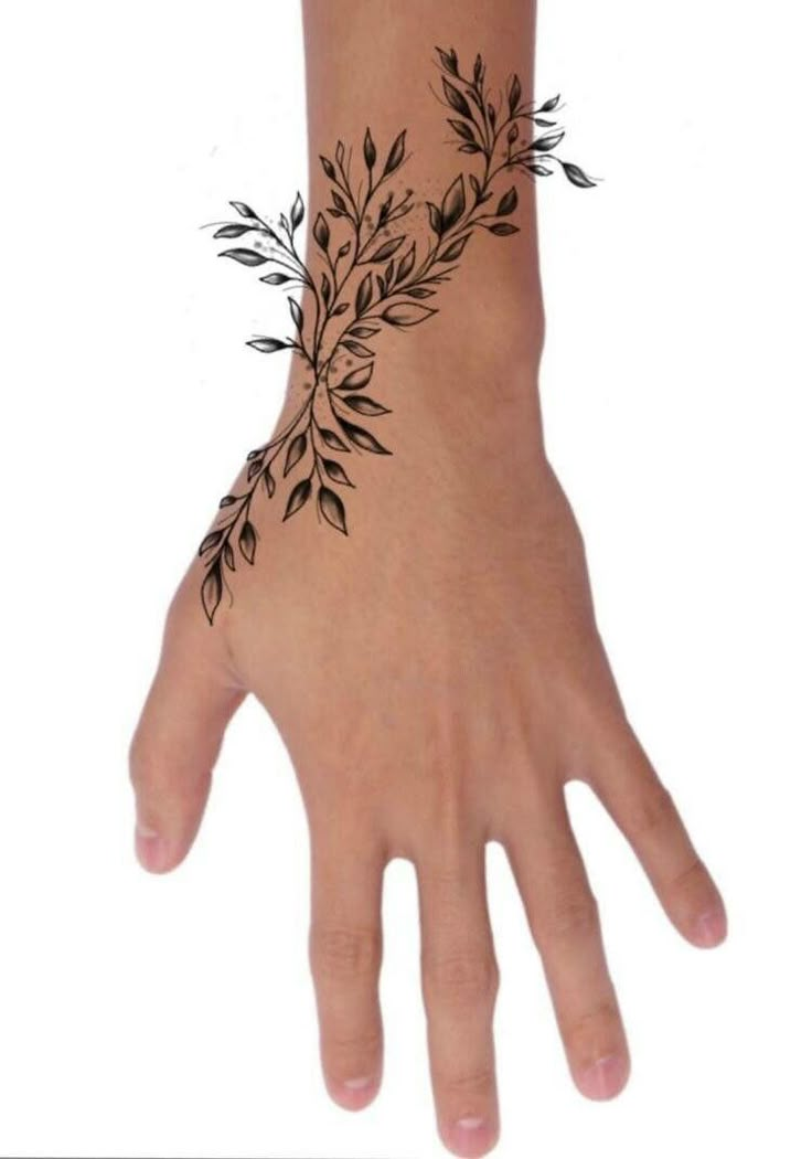 a person's hand with a black tattoo on the wrist and leaves drawn on it