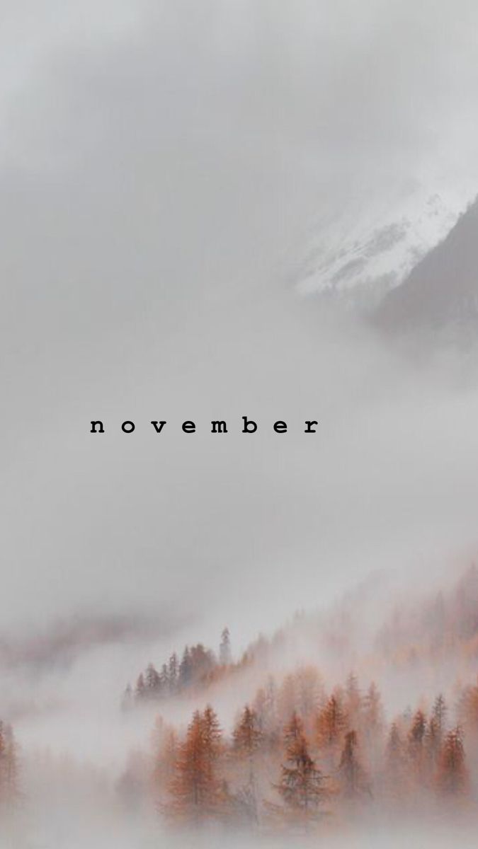 the words november are surrounded by fog and trees in front of a mountain range with low lying clouds