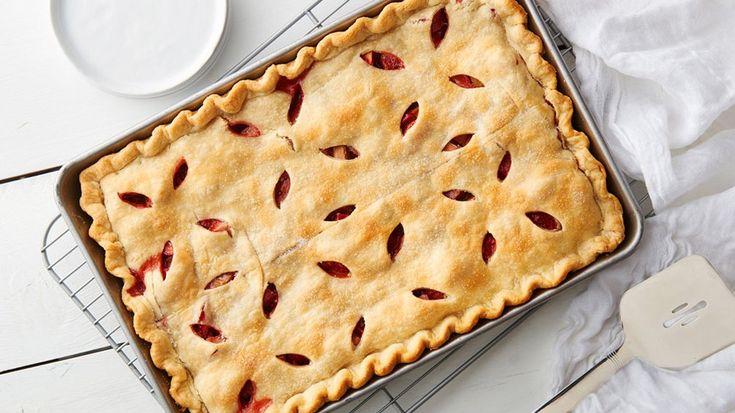 a pie sitting on top of a cooling rack next to a plate and spoons